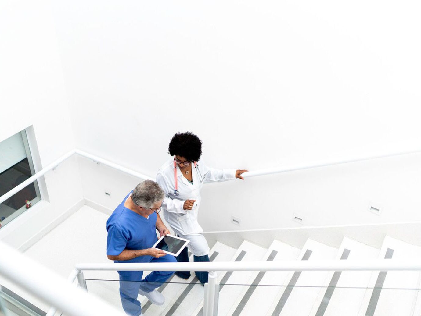 Two medical doctors on staircase having conversation 